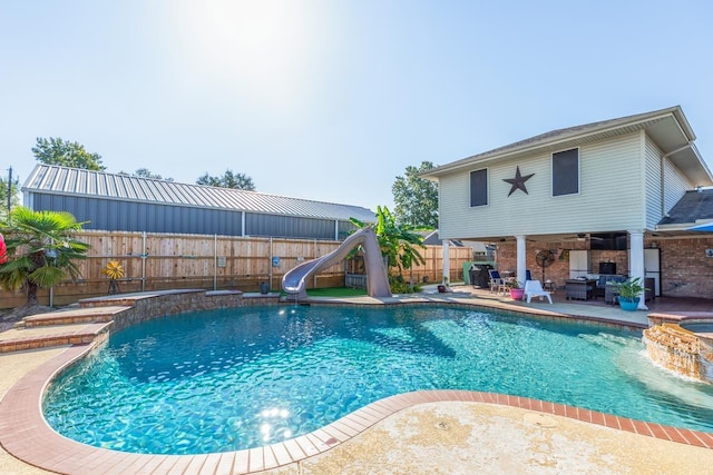 view of swimming pool with pool water feature, a water slide, a patio, and a hot tub