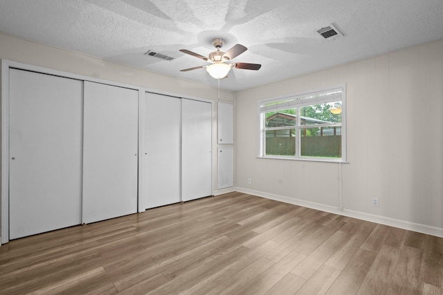 8598 Cornell Dr, Lumberton, TX 77657 - unfurnished bedroom featuring two closets, light wood-type flooring, a textured ceiling, and a ceiling fan