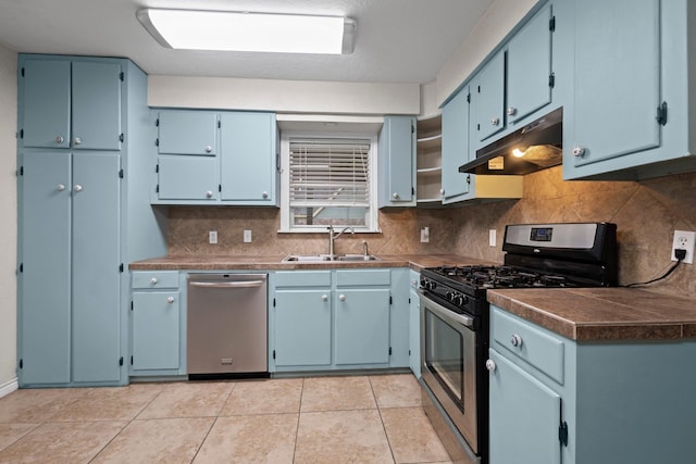 8598 Cornell Dr, Lumberton, TX 77657 - kitchen featuring stainless steel appliances, under cabinet range hood, backsplash, dark countertops, and blue cabinetry