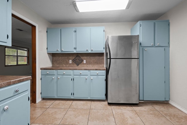 8598 Cornell Dr, Lumberton, TX 77657 - kitchen with freestanding refrigerator, blue cabinets, and light tile patterned floors