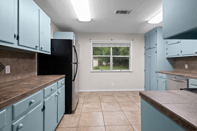 8598 Cornell Dr, Lumberton, TX 77657 - kitchen featuring a textured ceiling, blue cabinets, dishwasher, dark countertops, and backsplash