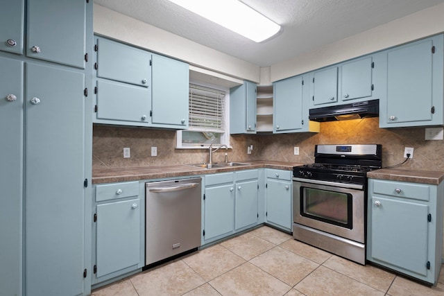 8598 Cornell Dr, Lumberton, TX 77657 - kitchen with stainless steel appliances, under cabinet range hood, backsplash, dark countertops, and light tile patterned flooring
