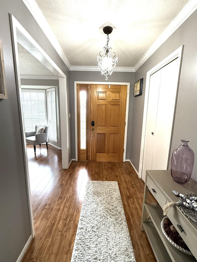 foyer entrance featuring an inviting chandelier, dark wood-style flooring, crown molding, and baseboards