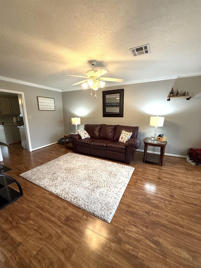 living room with crown molding, baseboards, ceiling fan, and visible vents