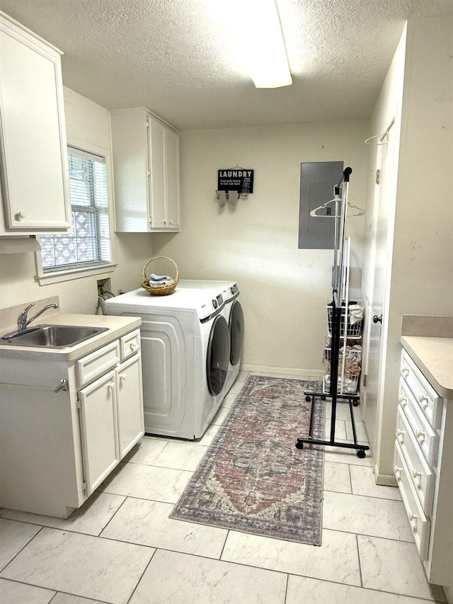 laundry room with a sink, a textured ceiling, cabinet space, and washing machine and clothes dryer