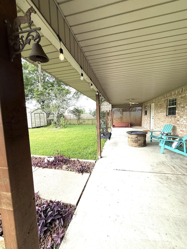 view of patio featuring a storage shed, fence, an outbuilding, and an outdoor fire pit