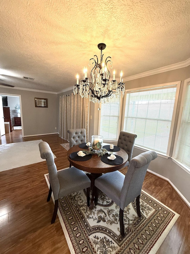 dining area featuring visible vents, crown molding, dark wood-type flooring, a textured ceiling, and a notable chandelier