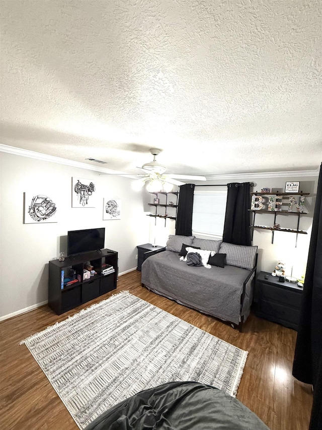 bedroom with crown molding, a textured ceiling, baseboards, wood finished floors, and visible vents