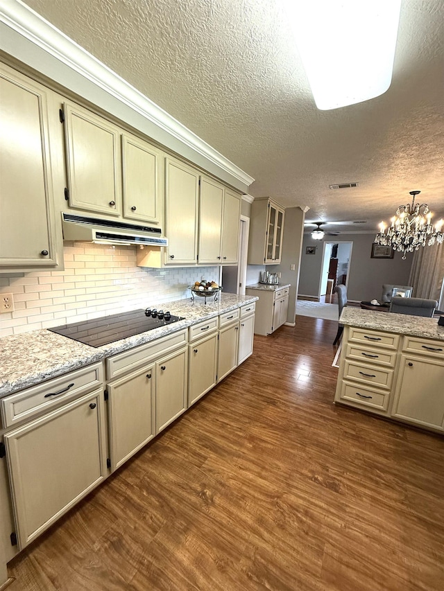 kitchen with black electric stovetop, a textured ceiling, ceiling fan with notable chandelier, under cabinet range hood, and dark wood-style floors