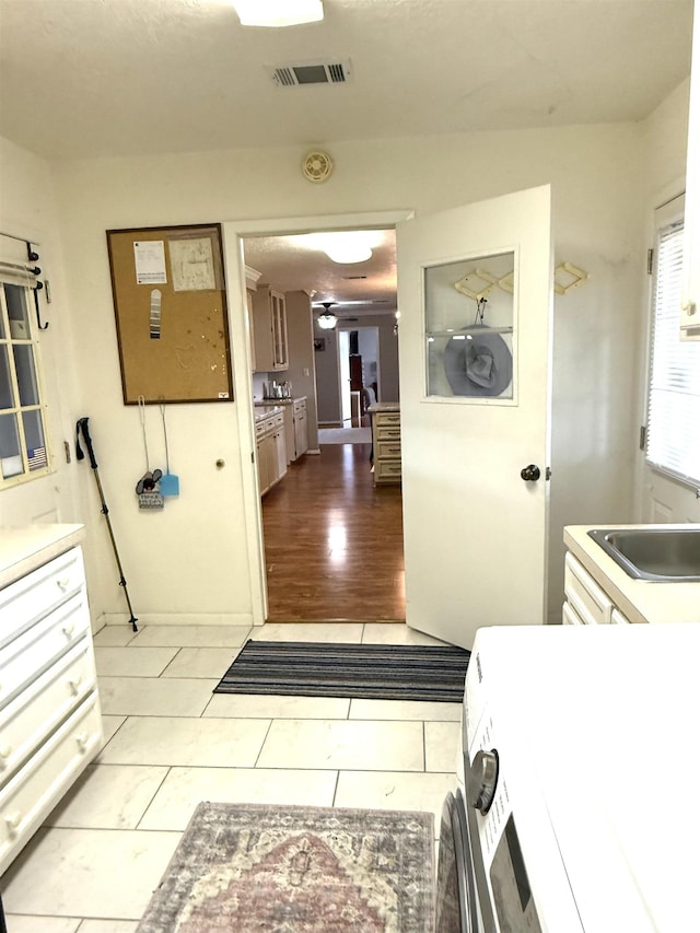 interior space featuring visible vents, ceiling fan, light countertops, a sink, and light tile patterned floors