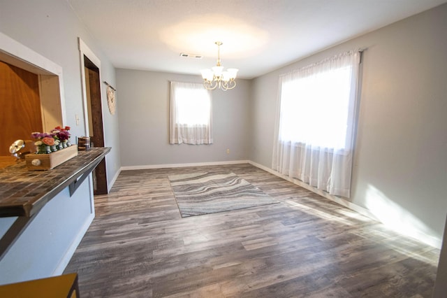 dining space with dark hardwood / wood-style floors and a chandelier