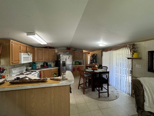 kitchen with white appliances, vaulted ceiling, kitchen peninsula, and a textured ceiling