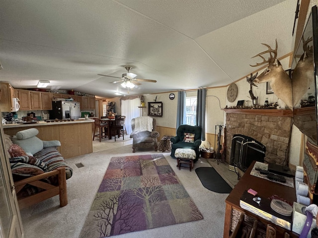 living room with a stone fireplace, lofted ceiling, ceiling fan, light carpet, and a textured ceiling