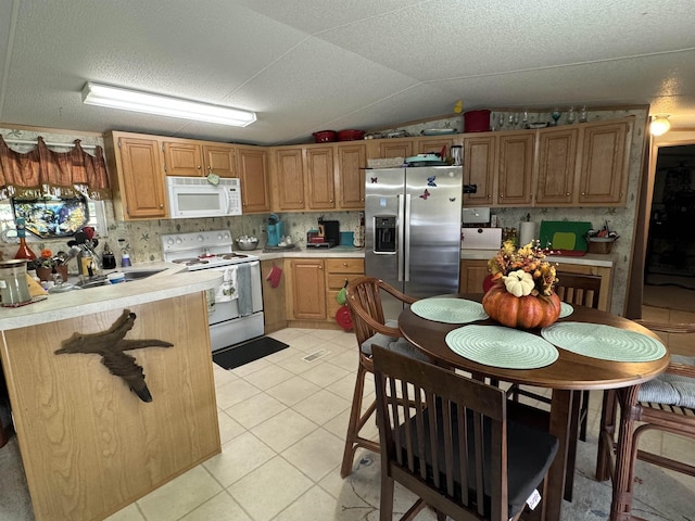 kitchen featuring lofted ceiling, sink, white appliances, light tile patterned floors, and a textured ceiling