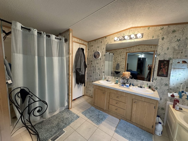 bathroom with vanity, a tub to relax in, tile patterned flooring, and a textured ceiling