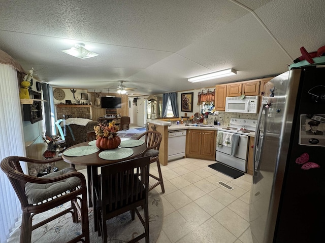 kitchen featuring white appliances, a textured ceiling, light tile patterned floors, kitchen peninsula, and ceiling fan