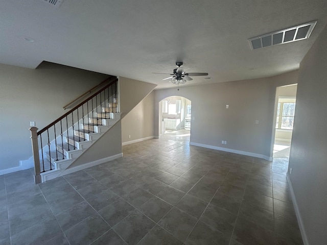 unfurnished room with arched walkways, ceiling fan, visible vents, and a healthy amount of sunlight