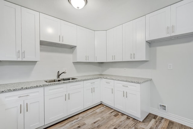 kitchen featuring white cabinets, light wood-type flooring, and sink