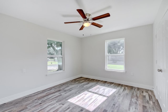 spare room with plenty of natural light, ceiling fan, and light wood-type flooring