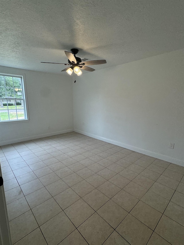 empty room featuring a textured ceiling, ceiling fan, and light tile patterned flooring