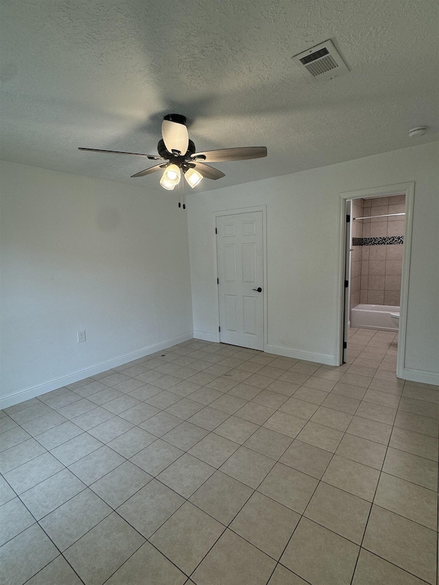 empty room with light tile patterned floors, a textured ceiling, and ceiling fan