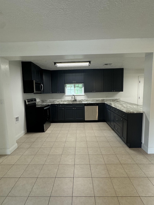 kitchen featuring light tile patterned floors, stainless steel appliances, light stone counters, and sink