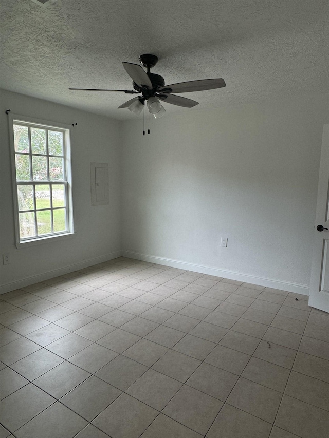 spare room with ceiling fan, light tile patterned floors, and a textured ceiling