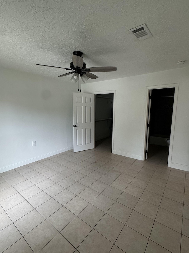 tiled empty room featuring ceiling fan and a textured ceiling