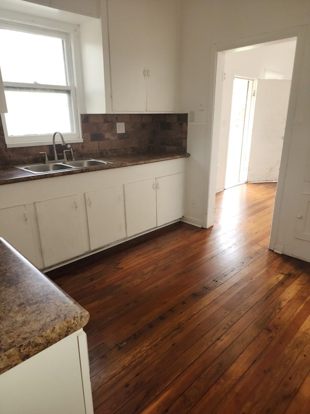 kitchen featuring backsplash, dark hardwood / wood-style flooring, sink, and white cabinets