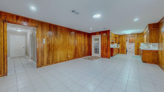 kitchen with crown molding, wooden walls, and light tile patterned floors