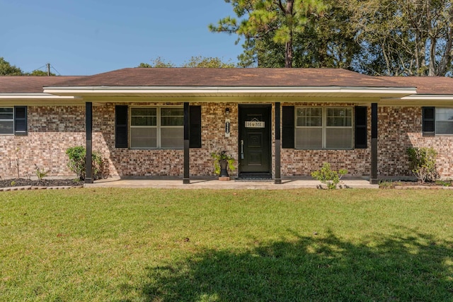 ranch-style house featuring covered porch and a front yard