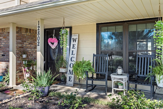 view of exterior entry featuring a porch and brick siding