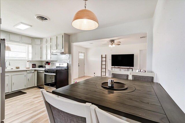 kitchen with decorative backsplash, stainless steel appliances, ceiling fan, pendant lighting, and plenty of natural light