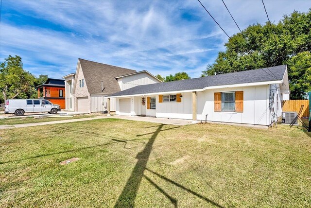 view of front of property with a front yard, a porch, central AC, and a garage