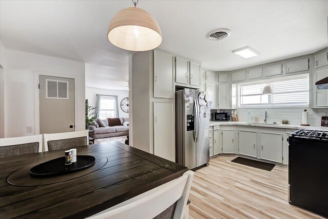 kitchen with sink, stainless steel refrigerator with ice dispenser, electric range, tasteful backsplash, and decorative light fixtures