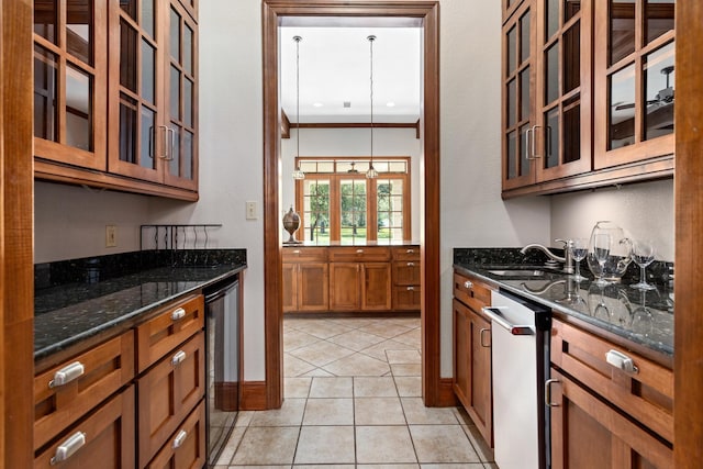 kitchen featuring dishwasher, dark stone counters, sink, crown molding, and decorative light fixtures