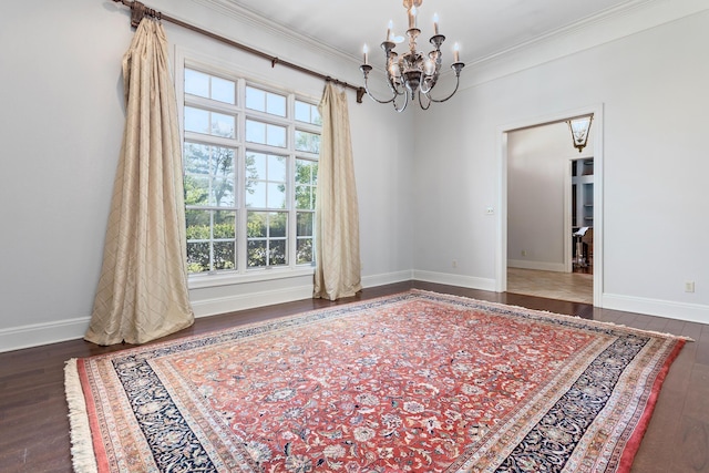 spare room featuring dark hardwood / wood-style flooring, ornamental molding, and a notable chandelier