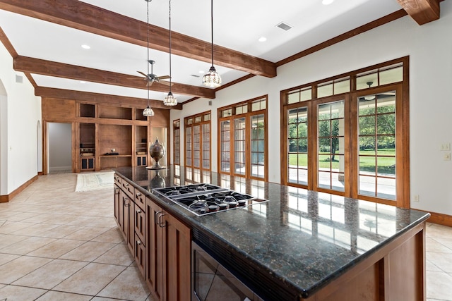 kitchen with a center island, hanging light fixtures, dark stone countertops, beam ceiling, and stainless steel appliances