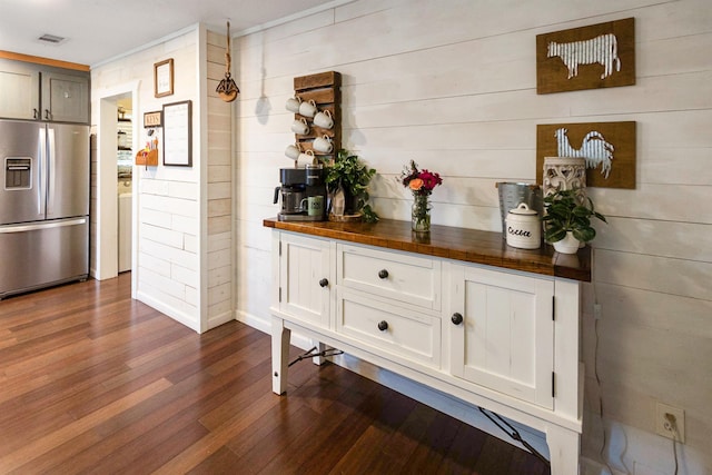 kitchen featuring wood walls, butcher block counters, stainless steel refrigerator with ice dispenser, dark hardwood / wood-style floors, and white cabinetry