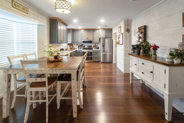 dining room featuring wooden walls, dark wood-type flooring, and sink