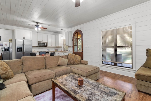 living room with hardwood / wood-style flooring, wood ceiling, ceiling fan, and wood walls