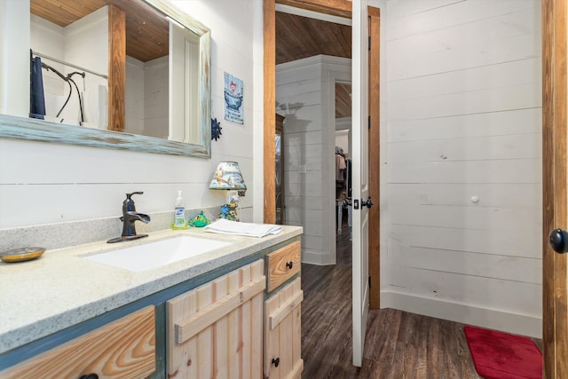 bathroom with wood walls, vanity, and hardwood / wood-style flooring