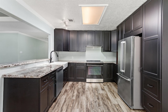 12795 Tanoak Ln, Beaumont, TX 77713 - kitchen featuring stainless steel appliances, a peninsula, light wood-type flooring, light stone countertops, and a textured ceiling