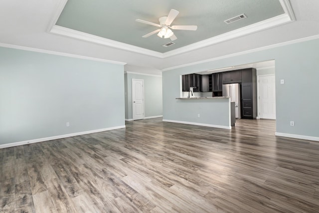 12795 Tanoak Ln, Beaumont, TX 77713 - unfurnished living room with a tray ceiling, a ceiling fan, dark wood-type flooring, and crown molding