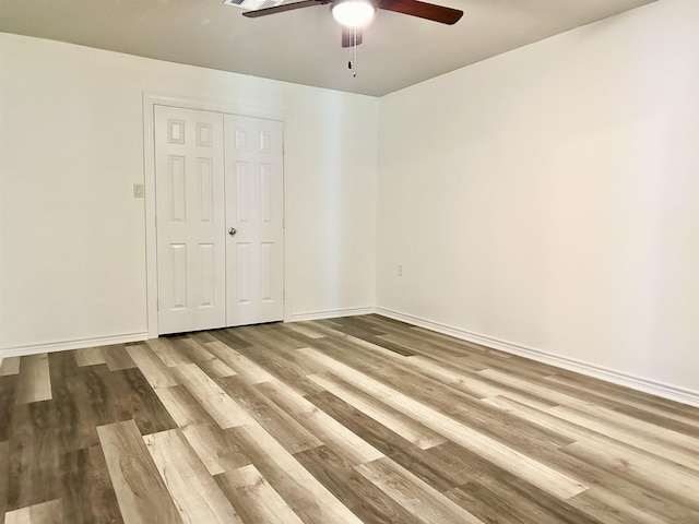 unfurnished bedroom with ceiling fan, light wood-type flooring, and a closet