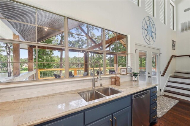 243 Riverbirch, Brookeland, TX 75931 - kitchen featuring blue cabinets, stainless steel dishwasher, high vaulted ceiling, dark wood-style floors, and decorative backsplash