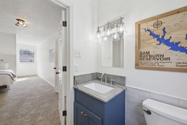 243 Riverbirch, Brookeland, TX 75931 - bathroom featuring vanity, toilet, a textured ceiling, and wainscoting