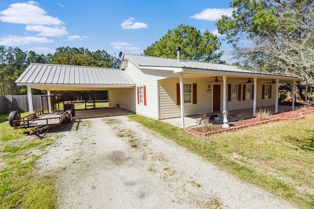 view of front of home featuring driveway, ceiling fan, metal roof, an attached carport, and fence