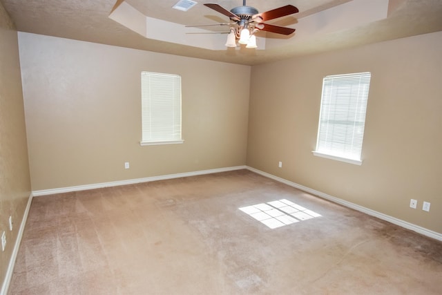 spare room with carpet flooring, a raised ceiling, a ceiling fan, and baseboards