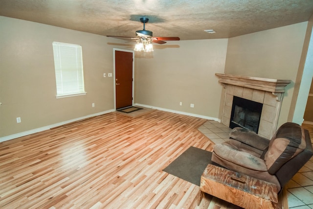 unfurnished living room featuring a textured ceiling, baseboards, wood finished floors, and a tile fireplace